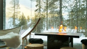 A cozy room with a hammock, a fire pit, and a view of a snowy forest. - Aavalevi Aurora Gielas, Top Of The Mountain (Levi)