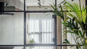 A modern living room with a sofa, a potted plant, and a large window. - Rusty Wave Loft in the heart of Klaipeda (Klaipeda)