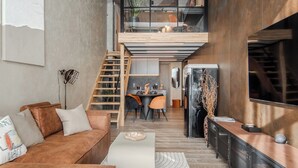 A modern interior with a loft-style dining area, a staircase, and a kitchen with a large refrigerator. - Rusty Wave Loft in the heart of Klaipeda (Klaipeda)