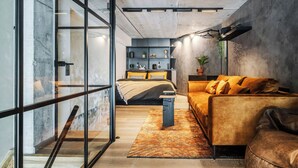 A modern bedroom with a bed, a sofa, and a glass partition. - Rusty Wave Loft in the heart of Klaipeda (Klaipeda)