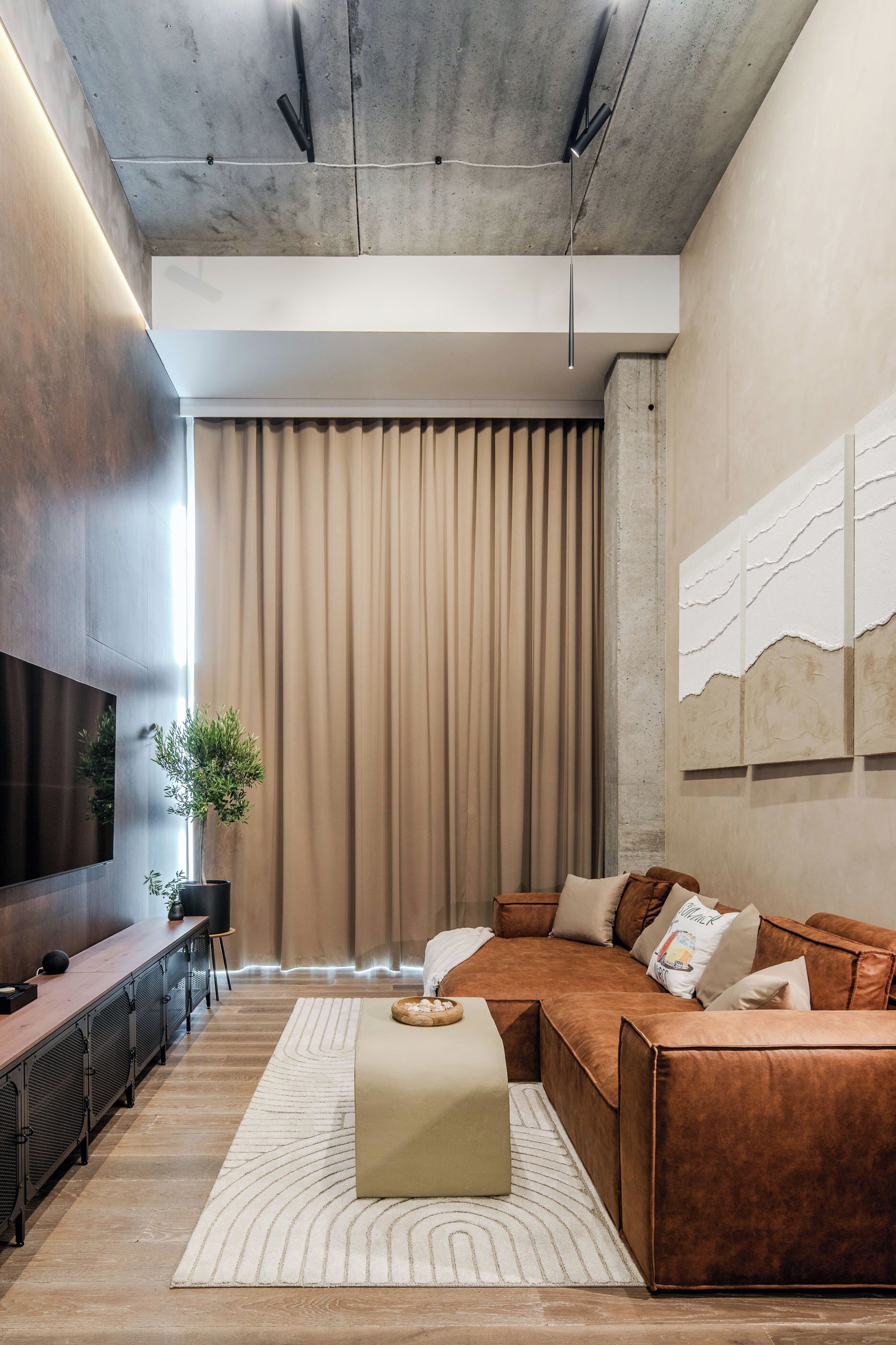 A modern living room with a sectional sofa, a flat-screen TV, a coffee table, and a large window with curtains.