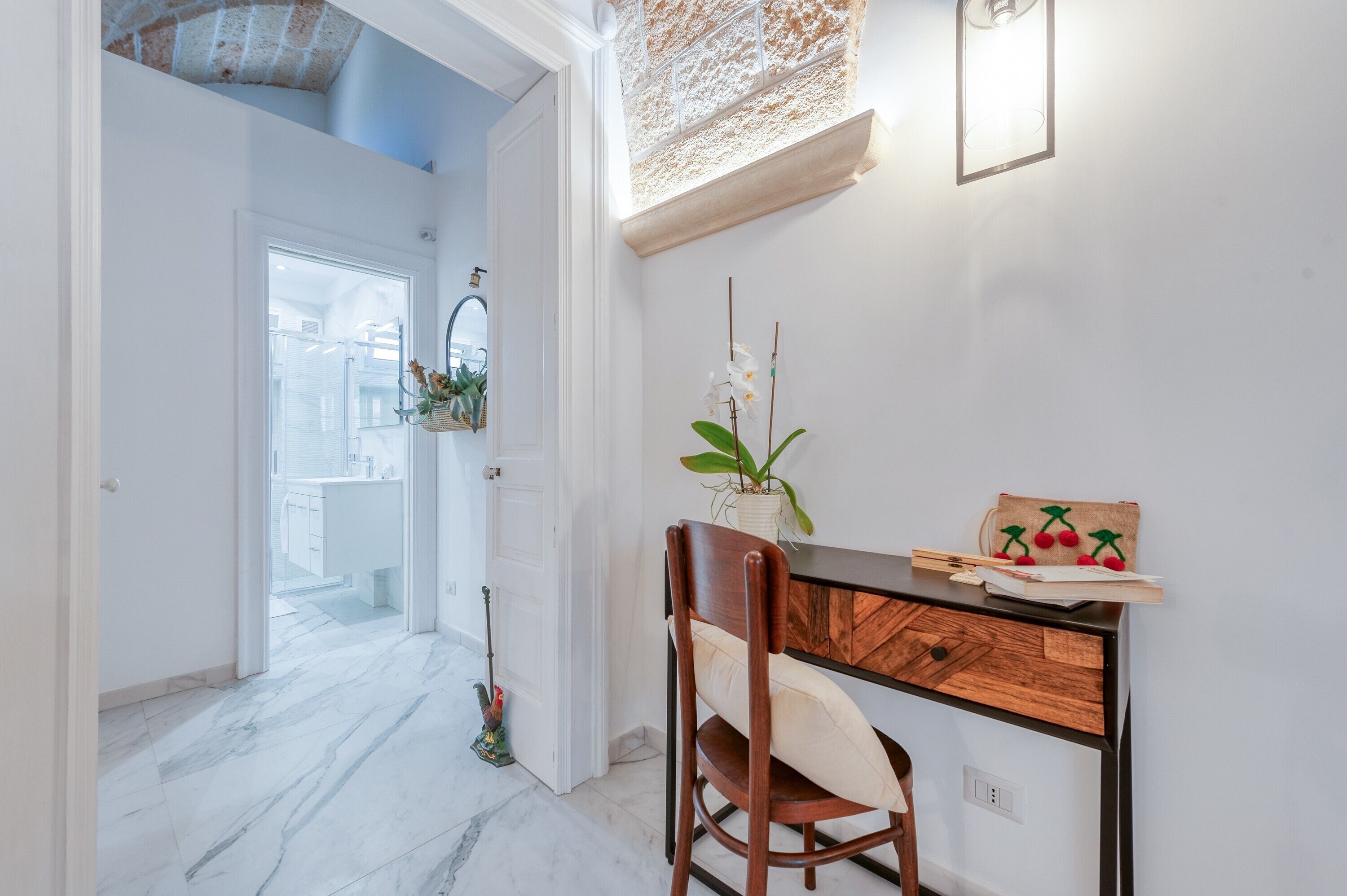 Una cucina moderna con una sedia in legno, un tavolino con oggetti decorativi e vista sulla stanza adiacente.