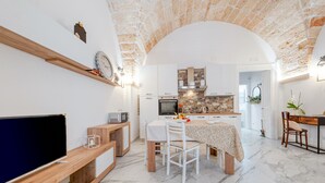 Une cuisine moderne avec des meubles blancs, un pare-feu en pierre et un coin repas comprenant une table et des chaises.