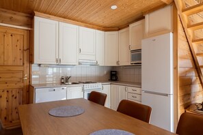 A kitchen with white cabinets, a stove, a microwave, and a refrigerator.