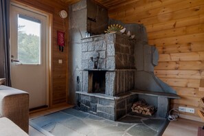 A stone fireplace with a chimney, a window with curtains, and a door. - Alpine Chalet Central By Aavalevi Holidays (Levi)