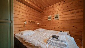 Una camera in una baita di legno con un letto, due lampade ai comodini e due quadri appesi al muro.