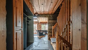 Ein Blockhaus-Interieur mit Steinboden, Holzwänden und einer gemütlichen Sitzecke mit Sofa und Sesseln.