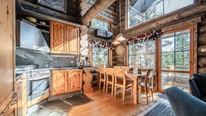 Ein rustikales Blockhaus-Interieur mit Küche, Essbereich und großen Fenstern.