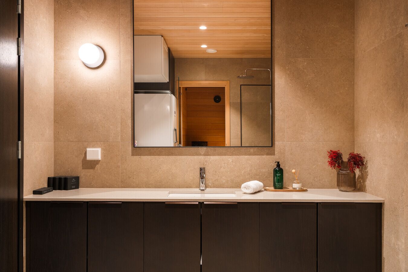 A modern bathroom with a large mirror, a sink, and cabinets.
