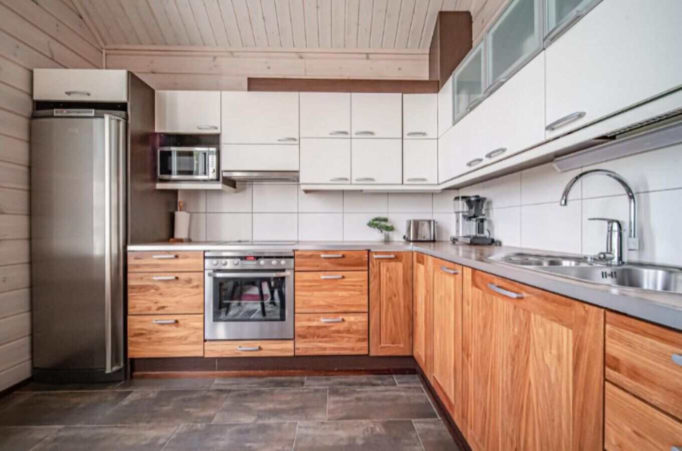 A modern kitchen with wooden cabinets, stainless steel appliances, and a tiled backsplash.