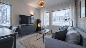 Una sala de estar moderna con chimenea, televisor de pantalla plana, sofá y zona de comedor.