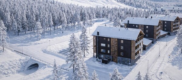 A snow-covered lodge with multiple floors, a ski lift, and a tunnel.