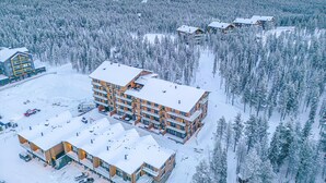 Useita kerroksia käsittävä majoitusrakennus, jonka keskellä on avoin sisäpiha, ja jonka ympärillä on tiheä metsä.