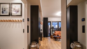 Moderni hotellihuone, jossa on puulattia, sohva, sohvapöytä ja suuret ikkunat, joista avautuu näkymä kaupungin ylle.