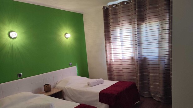 A room with two beds, green walls, and a window with striped curtains. - Casa dos Fetos - Rural vacation home in Portugal (Espite)