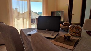 A laptop on a table with a view of a balcony and a TV in the background. - Casa dos Fetos - Rural vacation home in Portugal (Espite)