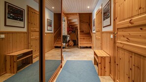 Un intérieur en bois avec un mur miroir, des bancs en bois, un escalier et des tableaux encadrés accrochés aux murs.