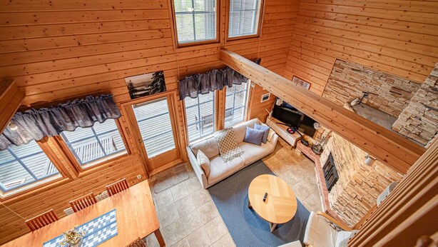 L’intérieur chaleureux d’un chalet avec un plancher en bois, un canapé, une table à manger et une cheminée.