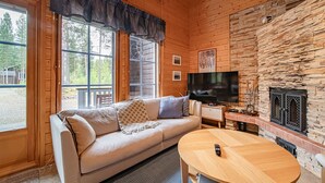 Un intérieur de chalet chaleureux avec un canapé, un téléviseur et une cheminée.