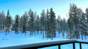 Escena nevada de un bosque con barandilla de balcón.