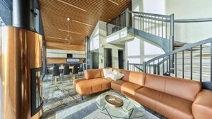 A spacious living area with a large sectional sofa, a glass coffee table, and a modern fireplace.