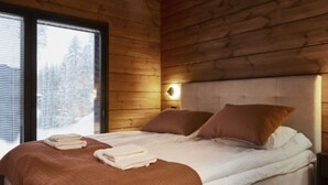 A wooden cabin bedroom with a bed, pillows, and a nightstand.