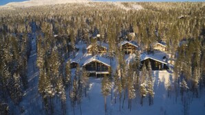 A snow-covered lodge with multiple cabins surrounded by dense forest.