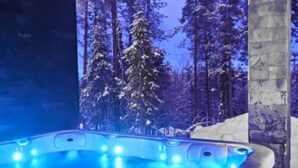 A hot tub with a view of snow-covered trees.