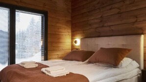A wooden cabin bedroom with a bed, pillows, and a nightstand.