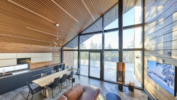A modern interior with a wooden ceiling, large windows, a dining area, and a fireplace.