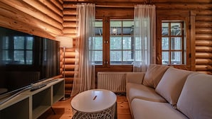Ein rustikales Holzhaus-Interieur mit Fernseher, Sofa und rundem Tisch.
