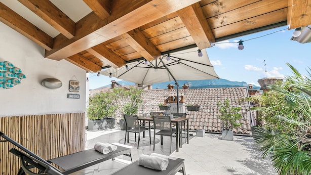 Une terrasse extérieure dotée d’un plafond en bois, d’une table avec des chaises et d’un fauteuil de relaxation.