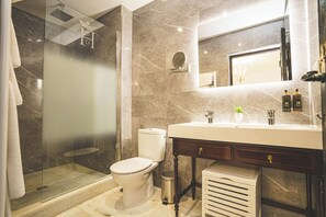 Et moderne badeværelse med bruseniche, toilet, vaskebord med spejl og håndvask.