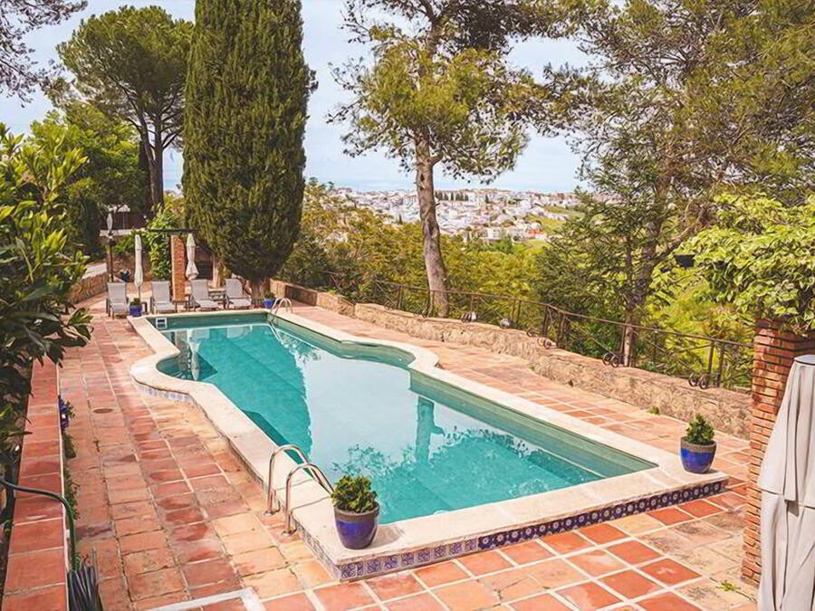 A rectangular swimming pool with a tiled edge, surrounded by a brick patio.