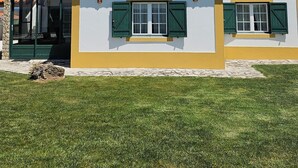 A two-story house with a tiled roof, green shutters, and a stone foundation. - Casa do Moinho, between the Lagoon and Óbidos Castle (Óbidos)