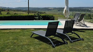 A poolside area with two lounge chairs and a covered umbrella, overlooking a landscaped garden and distant hills. - Casa do Moinho, between the Lagoon and Óbidos Castle (Óbidos)