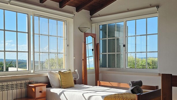 A bedroom with a wooden ceiling, large windows, a bed, a bedside table, and a radiator. - Casa do Moinho, between the Lagoon and Óbidos Castle (Óbidos)