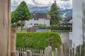 A residential area with a white house, a wooden fence, and a mountain backdrop.