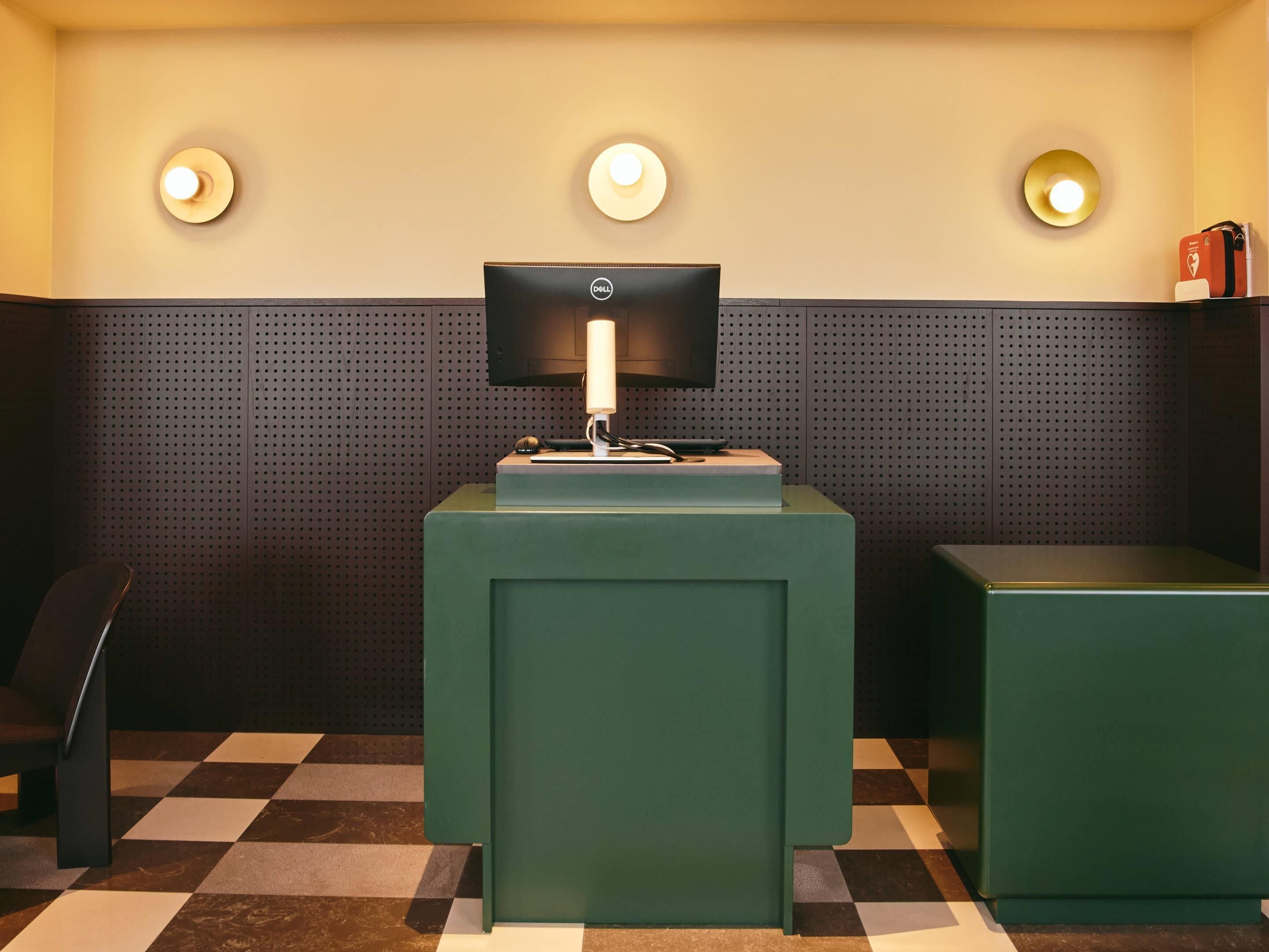 Une pièce avec un sol à carreaux, un bureau avec un écran d’ordinateur et une lampe.