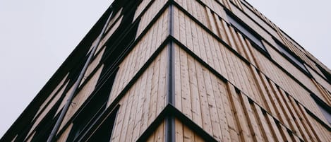 Un edificio moderno con fachada de madera y elementos estructurales negros.