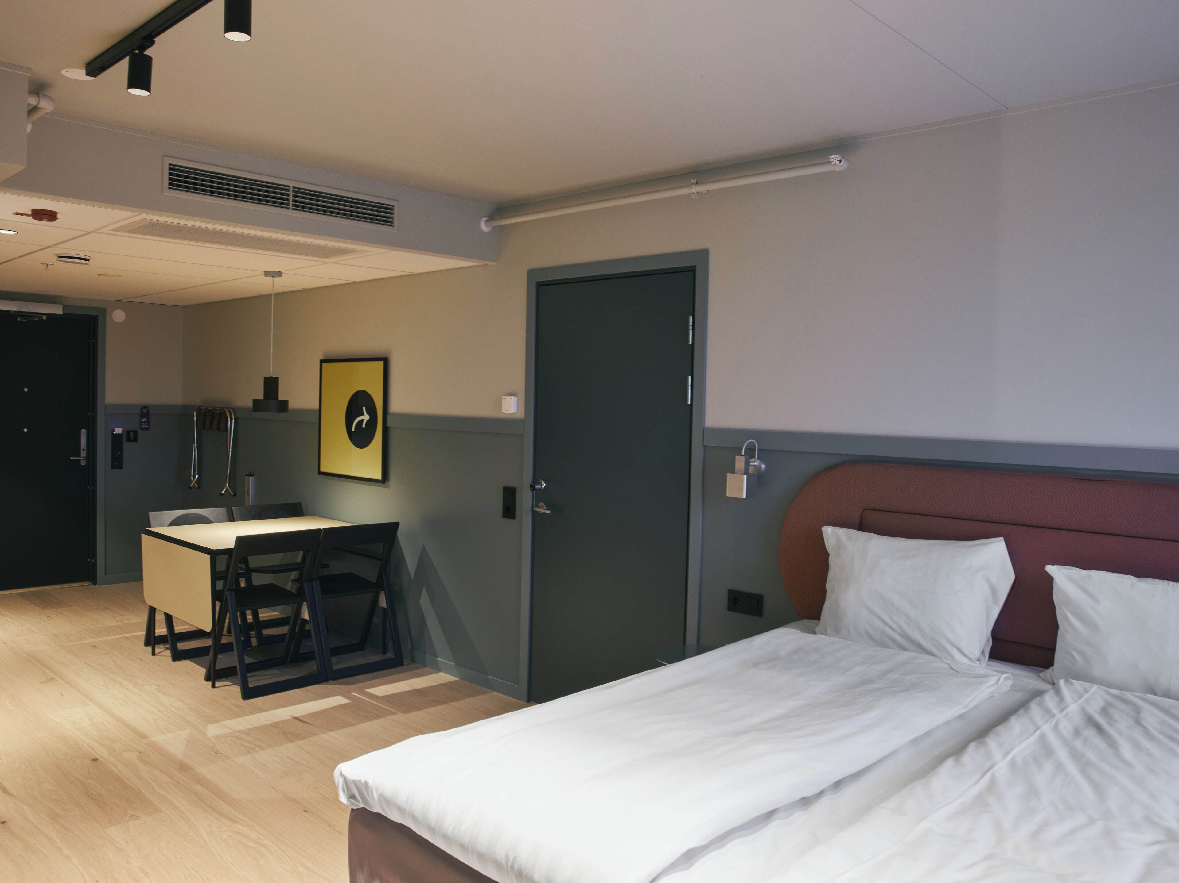 A hotel room with a bed, a desk, and a chair.