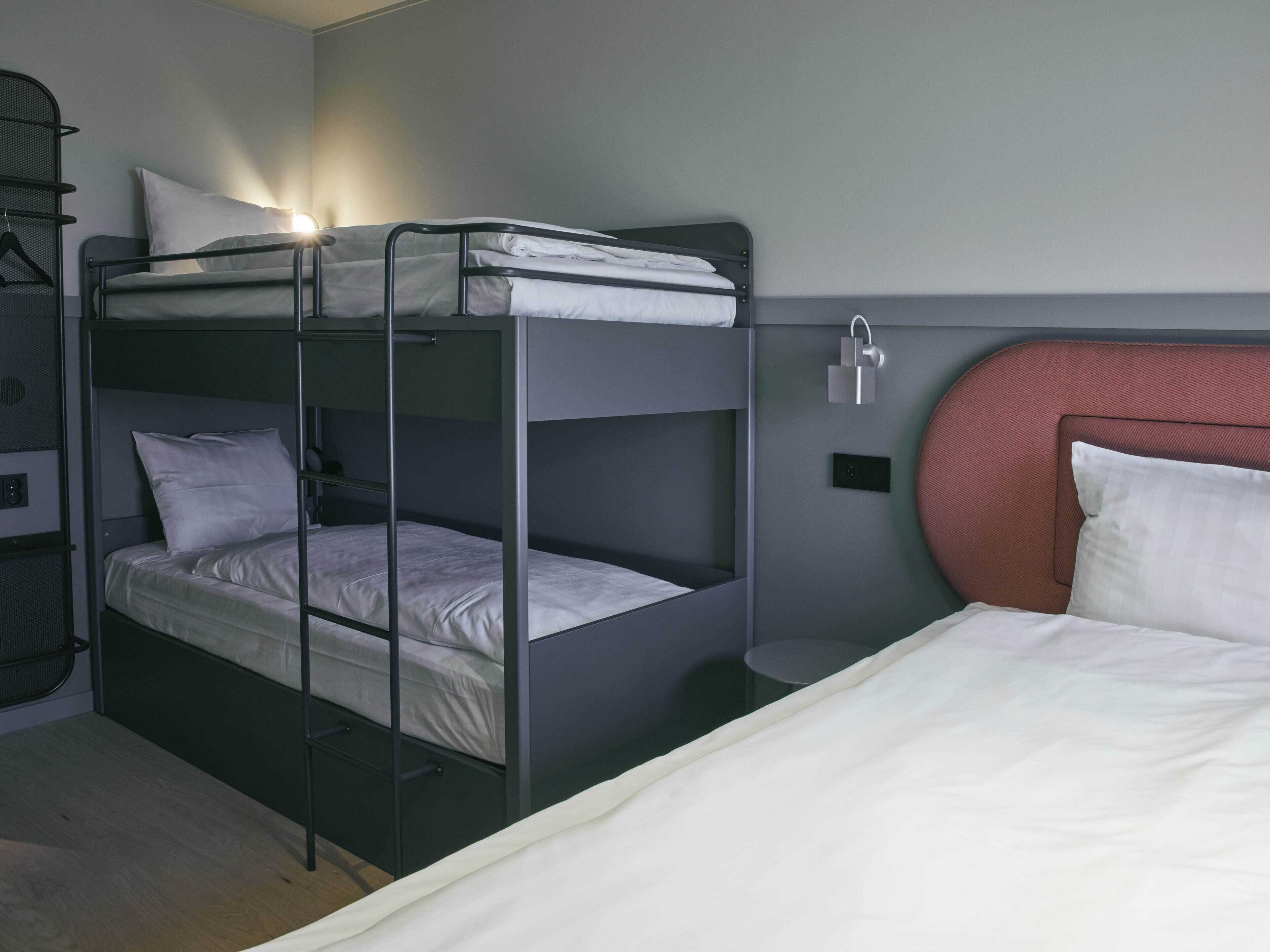 Een slaapkamer met een stapelbed aan de linkerkant en een enkel bed aan de rechterkant.