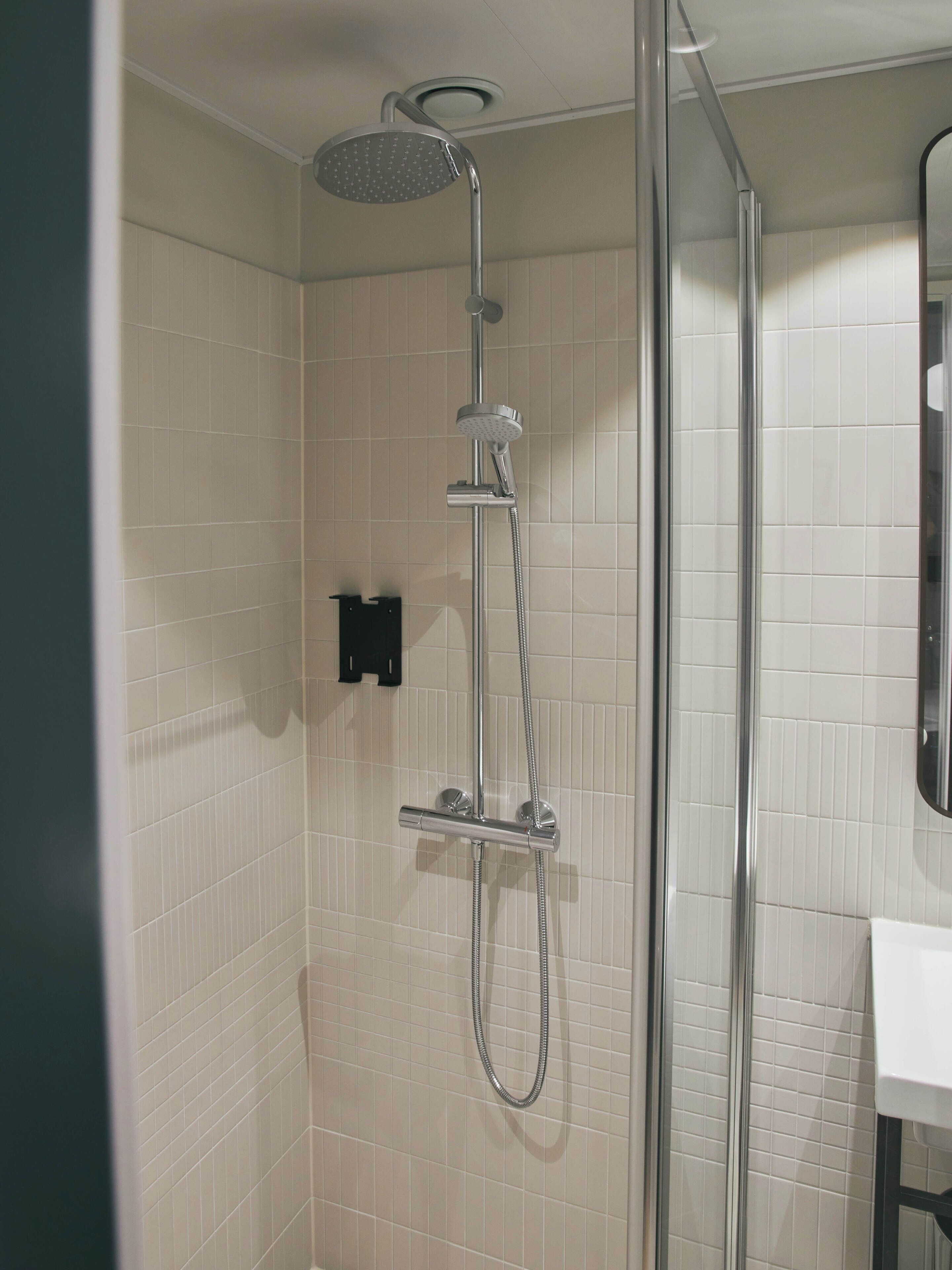 Une douche équipée d’un pommeau de douche à main et d’un robinet fixé au mur.