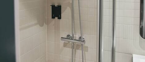 Une douche équipée d’un pommeau de douche à main et d’un robinet fixé au mur.