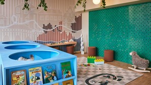 Zona de juegos infantiles con una mesa de juego azul, libros y un tren de juguete.