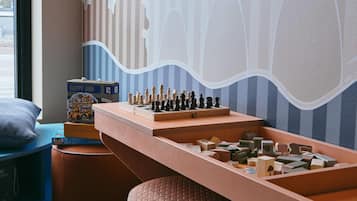 Una habitación con un tablero de ajedrez sobre una mesa de madera, una caja de acertijos y un mural con diseño a rayas.