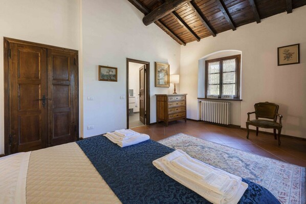 A bedroom with a bed, a dresser, a chair, and a window.