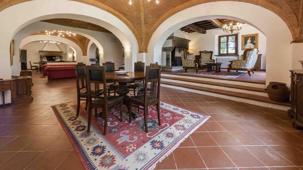 A spacious interior with arched ceilings, a central dining area, and a fireplace.