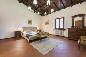 A bedroom with a bed, a sofa, a dresser, a mirror, and a chandelier.
