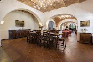 A spacious dining area with a high ceiling, arched ceilings, and a central table surrounded by chairs.